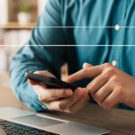 Person using smartphone and laptop with search bar overlay, representing search engine optimization (SEO) services.
