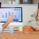 A man and woman collaborate at a desk, focused on a computer screen displaying SEO improvement strategies.