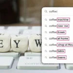 Search bar showing coffee keyword suggestions highlighted on screen over keyboard keys spelling “KEYWORD.”